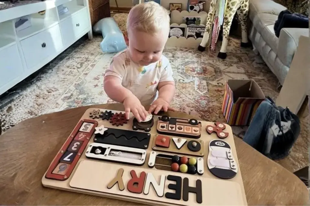 toddler playing a montessori busy board to develop fine motor skills