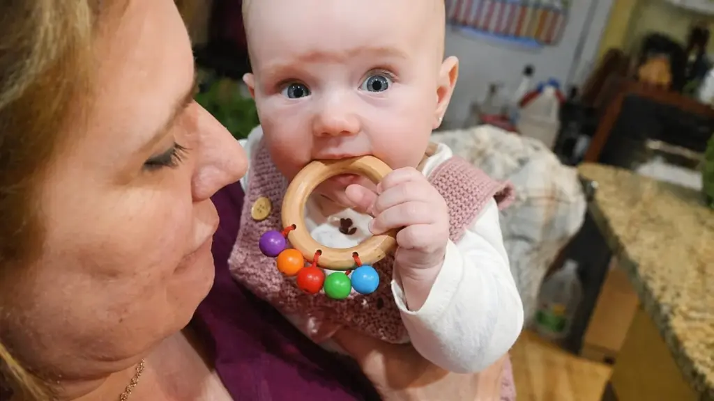 baby is mouthing a wooden rattle