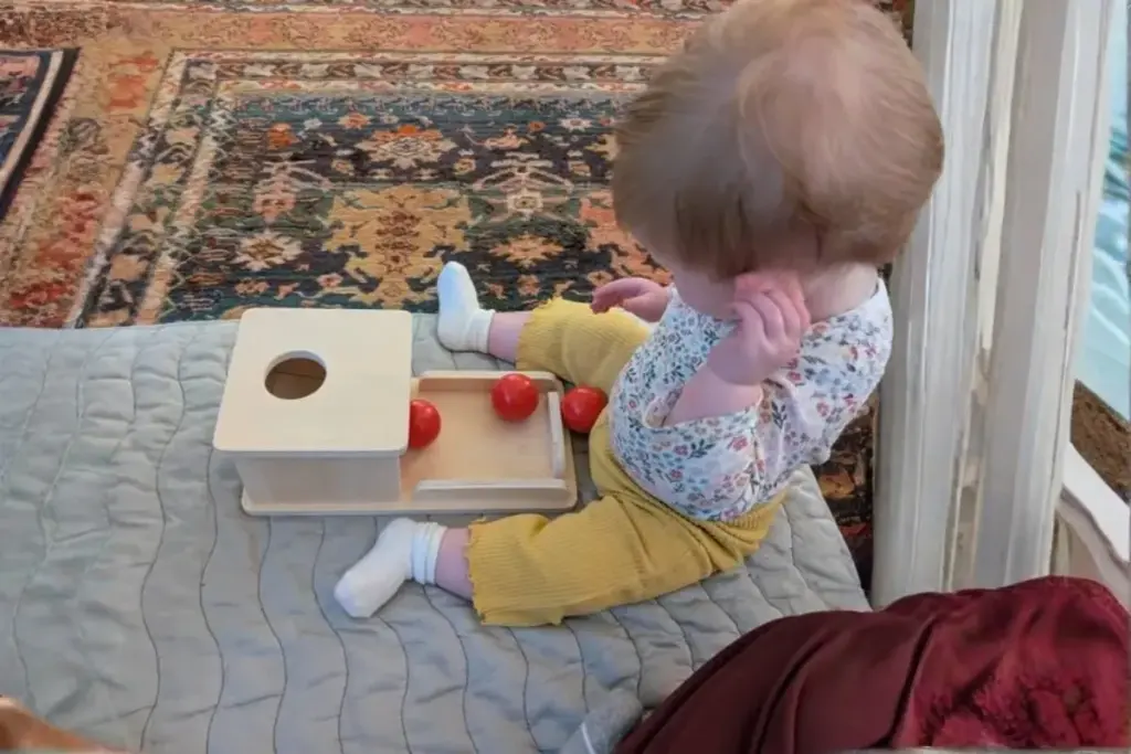 baby playing with a montessori object permanence box to develop cognitive skills