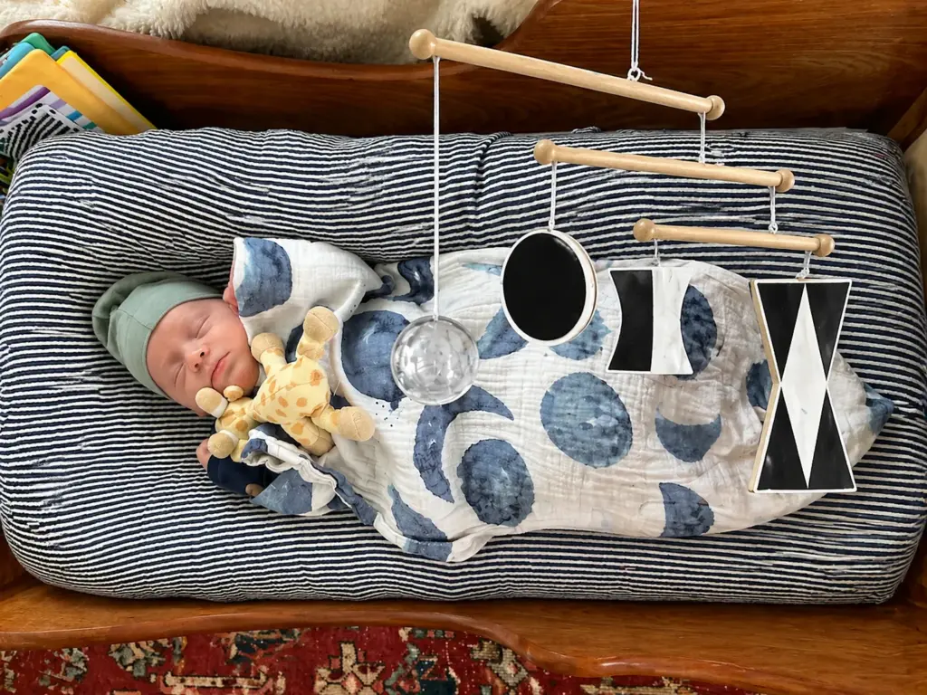 Baby lying under a Montessori mobile