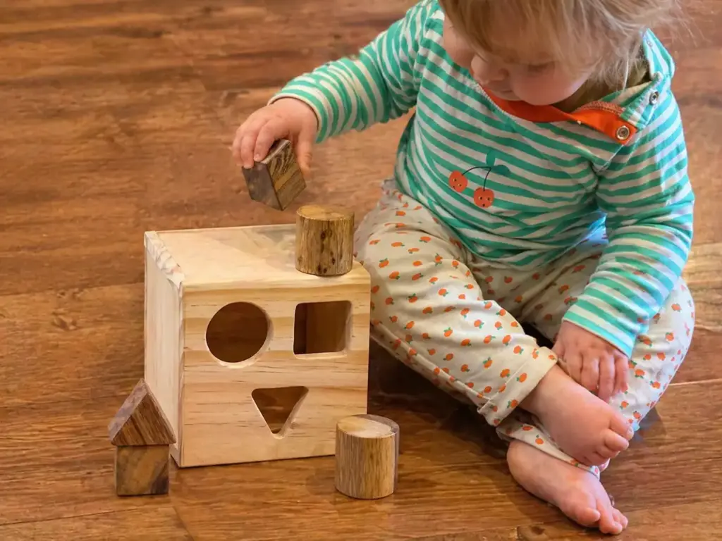 toddler playing with shape sorting box